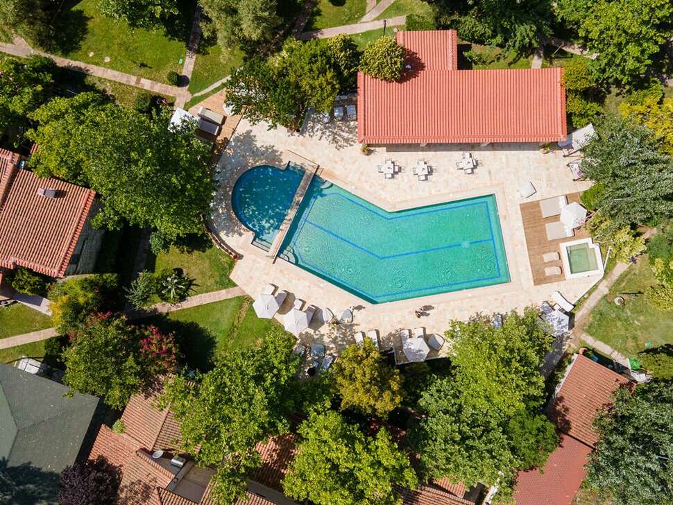 Overzicht over de groene tuin met het fijne zwembad bij Petrino Suites in Afitos, in Griekenland