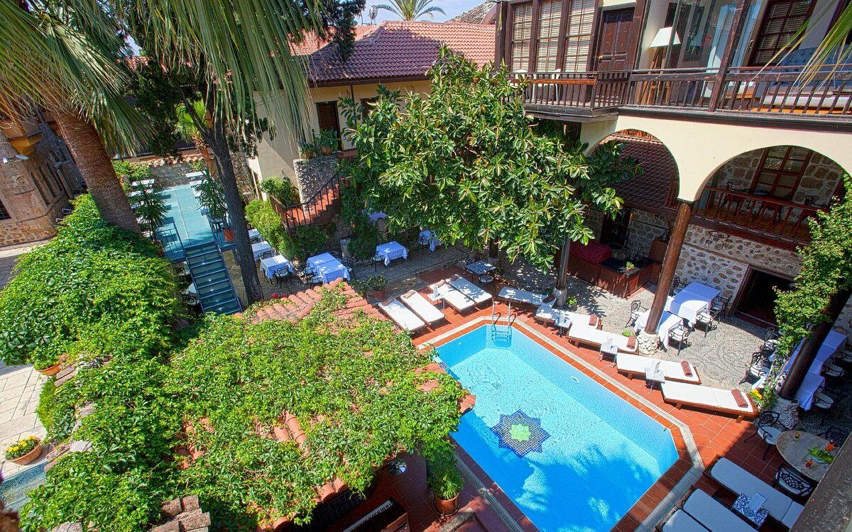 Heerlijke loungebedden aan het zwembad in de groene binnentuin van het kleinschalige hotel Alp Pasa in Antalya in Turkije