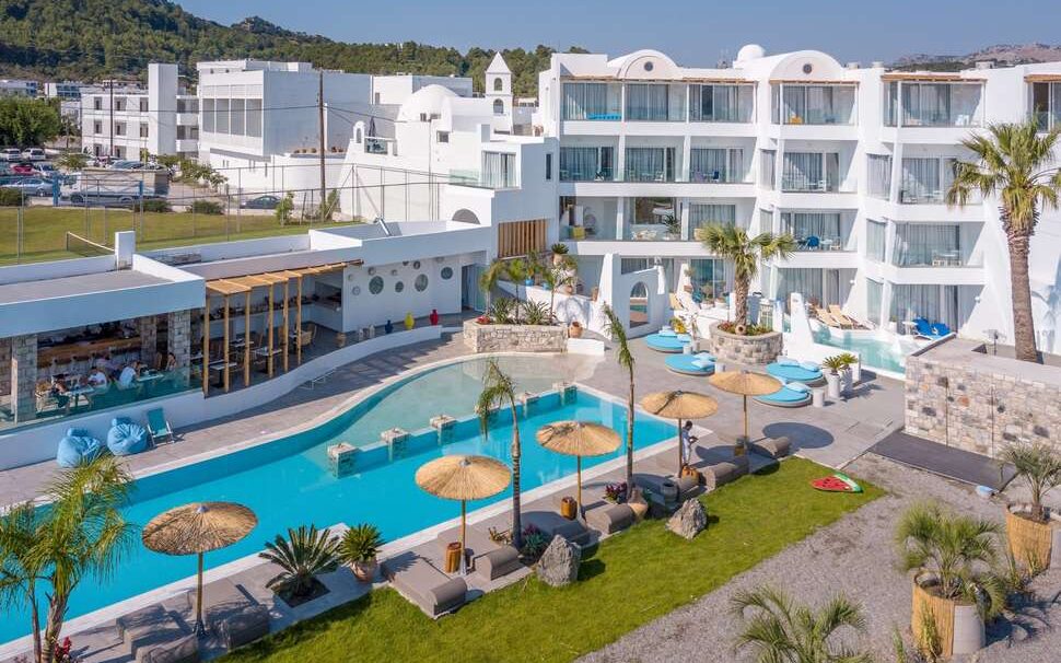 Geniet op je ligbedje onder een parasol aan het zwembad van het kleinschalige hotel Kouros Home in Faliraki