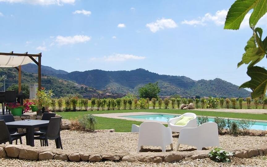 Het geweldige uitzicht op de groene heuvels vanaf het zwembad van het kleinschalige hotel Tenuta Edoné op Sicilië