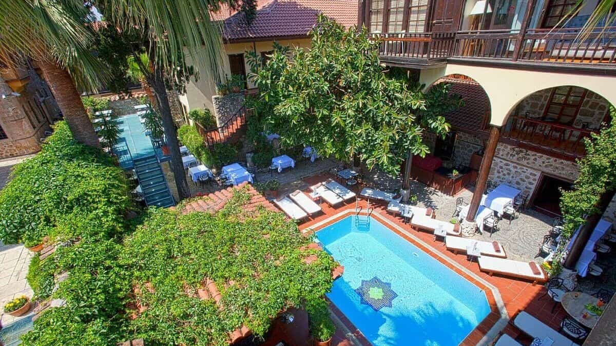 Heerlijke loungebedden aan het zwembad in de groene binnentuin van het kleinschalige hotel Alp Pasa in Antalya in Turkije